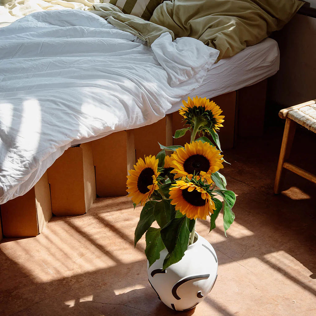 yellow sunflowers against the backdrop of Bett 2.0, an eco-friendly cardboard bed frame by RIAB USA